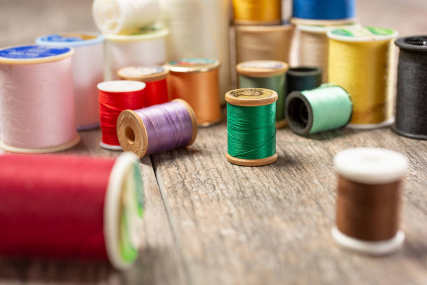 A closeup view of a variety of of thread spools in different colors, on a wooden surface. - Foto, immagini