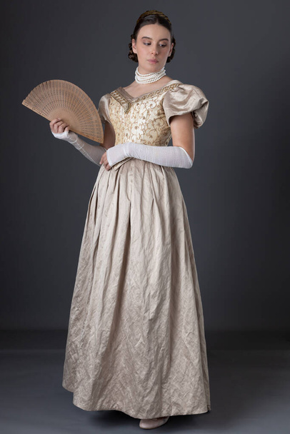 Victorian nainen yllään kulta pallo puku pitkä, pitsi sormeton käsineet ja seisoo harmaata taustaa vasten - Valokuva, kuva