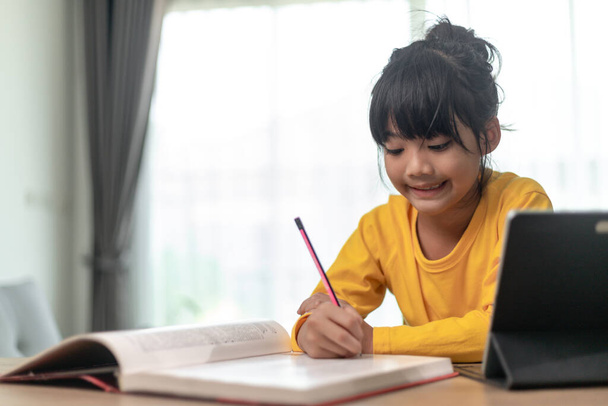Asijské holčička přičemž třída on-line a šťastný pro domácí školou karanténa coranavirus pandemický koncept - Fotografie, Obrázek