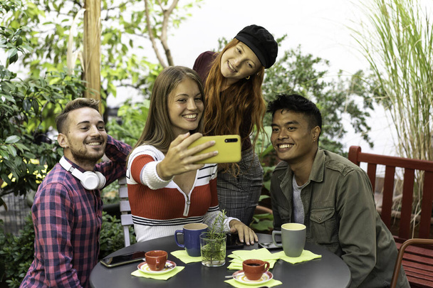 Amigos felizes multiculturais se divertindo tirando um retrato de selfie de grupo no jardim durante uma pausa para café - Jovens de raça mista rindo juntos desfrutando de um dia de férias - Foto, Imagem