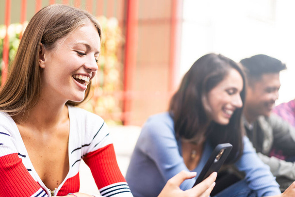 Glückliche multikulturelle Freunde mit Smartphone in der Uni-Pause - Menschen teilen Trendinhalte mit Mobiltelefonen - Technologiekonzept mit immer vernetzten Teenagern - Heller Filter - Foto, Bild