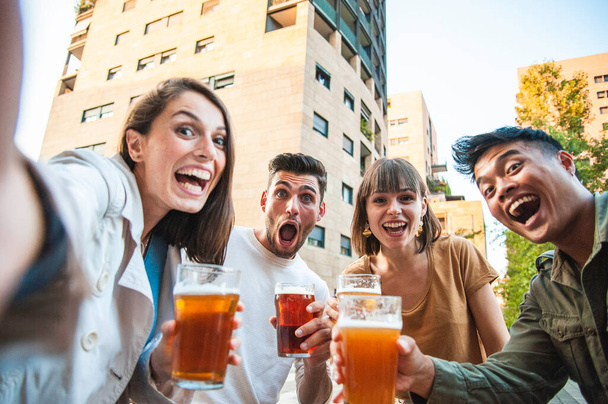 Amici felici che fanno selfie mentre bevono birra al pub all'aperto in città - Concetto di stile di vita amichevole con giovani multiculturali millenari che si divertono insieme - Filtro luminoso - Foto, immagini