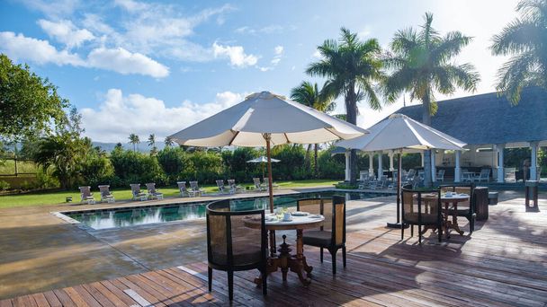 basen z krzesłami plażowymi i stołem obiadowym w luksusowym kurorcie, basen tropikalny - Zdjęcie, obraz
