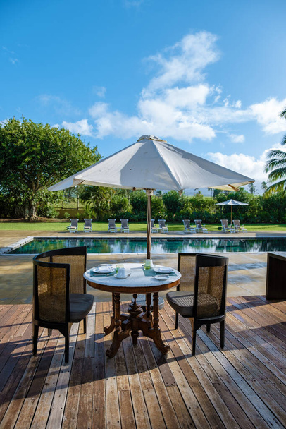 piscina con sillas de playa y mesa de almuerzo en un resort de lujo, piscina tropical - Foto, imagen