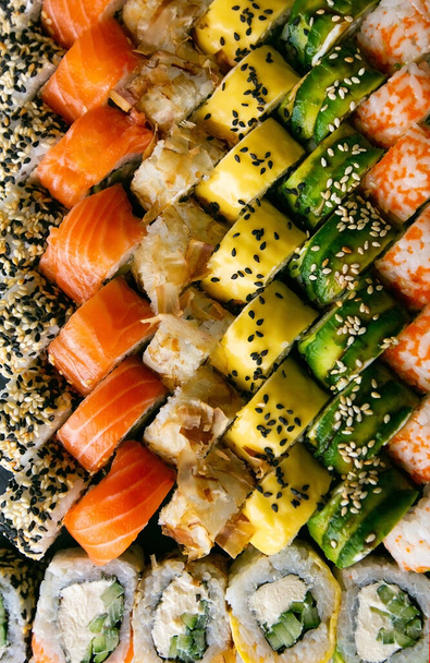 Surtido de rollos de sushi japonés sobre fondo negro. Marco de comida asiática o japonesa
 - Foto, imagen