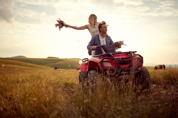 Romantic newlyweds driving quad together in the nature; Rural wedding concept - Foto, Imagem