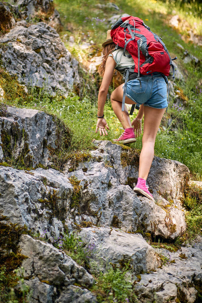 A sexy girl is climbing over the rocks while hiking the mountain on a beautiful day. Trip, nature, hiking - Foto, imagen
