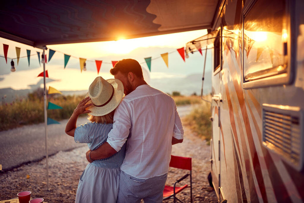A young couple in love enjoying romantic moments at the campsite at a beautiful sunset in the nature. Relationship, vacation, camping, nature - Foto, imagen