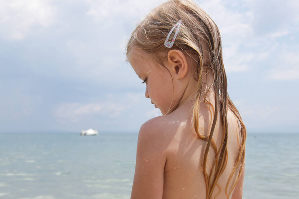 Het lange haar van een kind op het strand. Nat haar dichtbij beeld. Haarschade als gevolg van zoute oceaan water en zon, zomer haarverzorging concept. - Foto, afbeelding