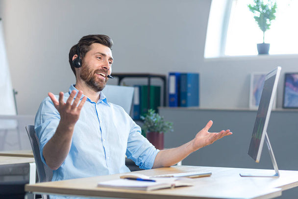A happy surprised call center employee works in the office with a headset for a video call - Foto, Imagem