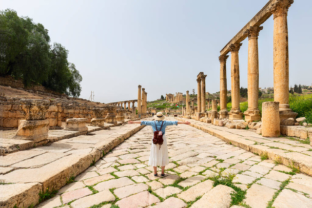 young woman tourist in color dress and hat leading man to South gate of the Ancient Roman city of Gerasa, modern Jerash, Jordan. Traveling together.  - Φωτογραφία, εικόνα