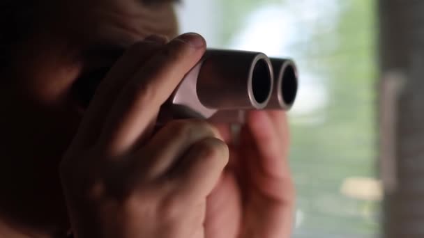 Mies vakoilee ihmisiä, käyttää kiikareita tarkkailuun - Materiaali, video