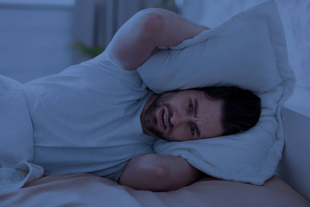 Le type au lit se couvre la tête avec un oreiller - Photo, image