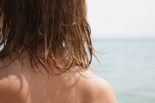 ビーチで女性の髪。濡れた髪がイメージを閉じます。塩辛い海の水と太陽、夏のヘアケアの概念による髪の損傷. - 写真・画像