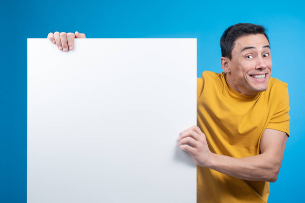 Excited man showing blank banner in studio - Фото, изображение
