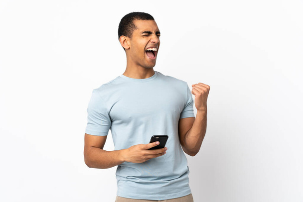 African American man over isolated white background with phone in victory position - Fotoğraf, Görsel