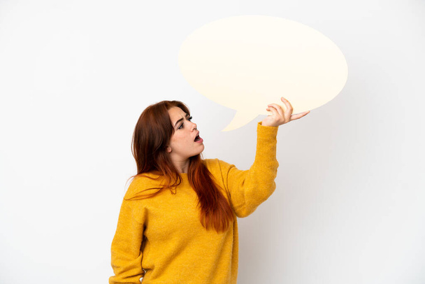 Young redhead woman isolated on white background holding an empty speech bubble - Photo, Image