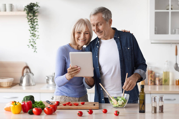 Senior paar lezen recept op digitale Tablet in de keuken - Foto, afbeelding