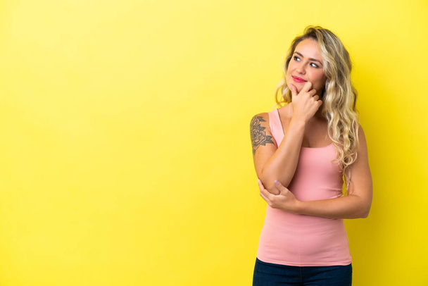 Young Brazilian woman isolated on yellow background looking to the side and smiling - Photo, Image