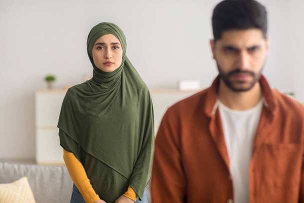 Δυστυχισμένη Μουσουλμάνα σύζυγος στέκεται πίσω από τους συζύγους - Φωτογραφία, εικόνα