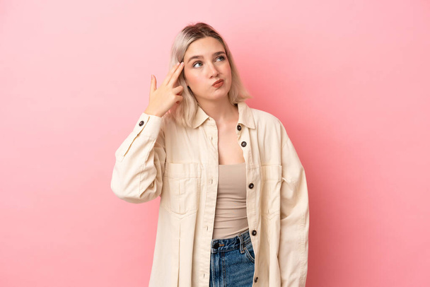 Young caucasian woman isolated on pink background with problems making suicide gesture - Foto, imagen