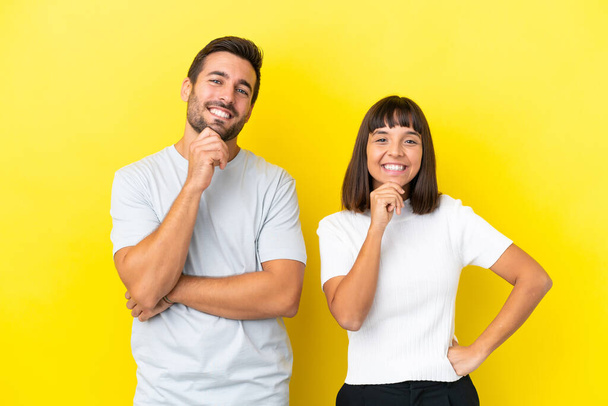 Young couple isolated on yellow background smiling with a sweet expression - Photo, Image