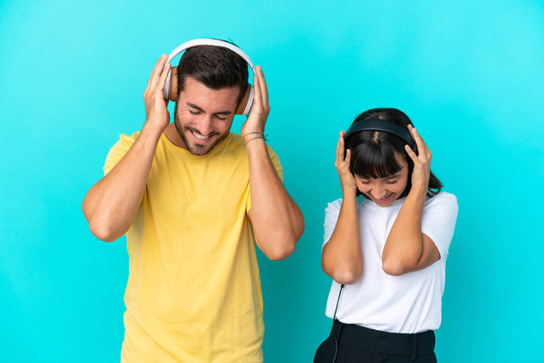 Young couple isolated on blue background listening music - Φωτογραφία, εικόνα