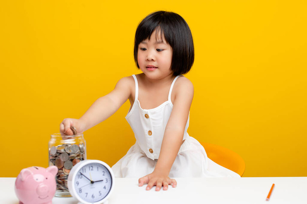 Asian girl's hand Put the coin in the piggy bank. A cute girl who is saving herself money for her own education. money saving concept - Photo, Image