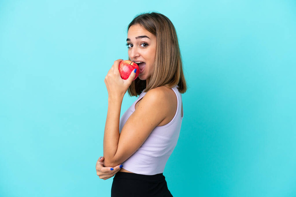 Joven mujer caucásica aislada sobre fondo morado comiendo una manzana - Foto, Imagen
