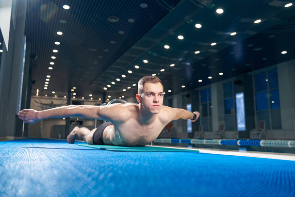 Male swimmer doing exercises on yoga mat swimming pool - Valokuva, kuva