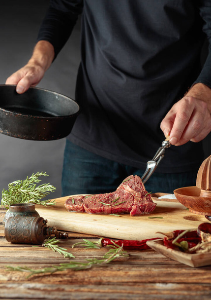 Chef préparer un steak. Steak non cuit en sauce avec épices un romarin sur une vieille table en bois
. - Photo, image