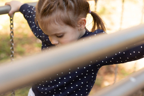 Pieni kaunis tyttö punottu letti on hauskaa epätasainen baareissa puistossa - Valokuva, kuva