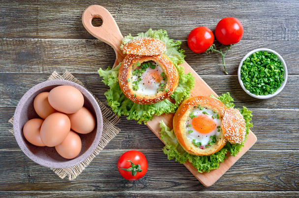 Bun γεμιστό με αυγό, φρέσκα βότανα, αυγά αγρόκτημα πάνω άποψη σε ένα ξύλινο φόντο. Η έννοια του πρωινού, συνταγές από αυγά. - Φωτογραφία, εικόνα