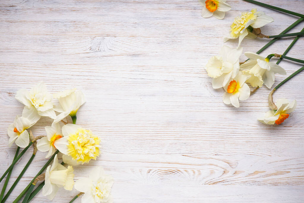 narcissen bloemen op een houten lichte achtergrond, plaats voor tekst, bovenaanzicht. - Foto, afbeelding