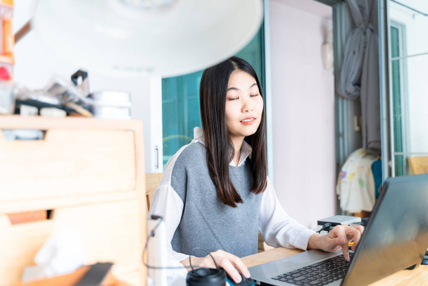Jonge mooie aziatische zakenvrouw met notebook in het thuiskantoor - Foto, afbeelding