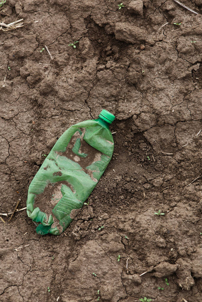 Ympäristön saastuminen, tyhjä pullo makaa paljaalla maalla  - Valokuva, kuva