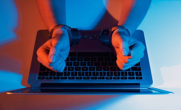 Man in handcuffs at the computer. Cyber crime concept - Foto, Imagen