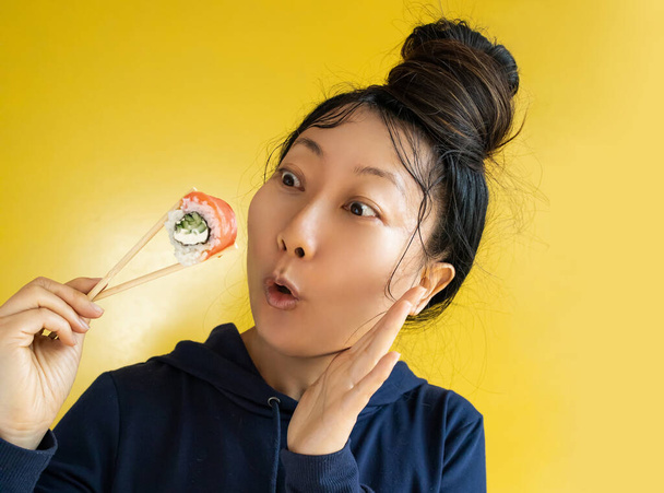 japanese girl eating sushi with chopsticks close up, food takeout and delivery service, salmon sushi rolls, tasty meal, sushi delivery - Photo, image