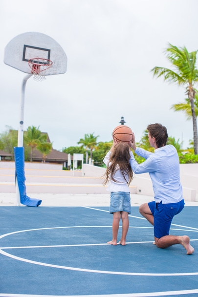 Junger Mann und kleines Mädchen spielen draußen im exotischen Resort Basketball - Foto, Bild