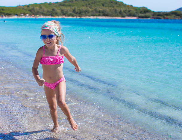 schattig meisje plezier in ondiep water hebben op tropisch strand - Foto, afbeelding