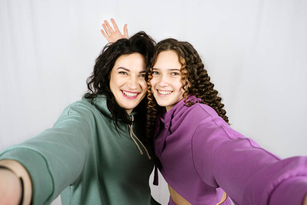 Portrait of happy mom and teen daughter spend time together. Teenage girl hugging her mother and having fun together - Zdjęcie, obraz