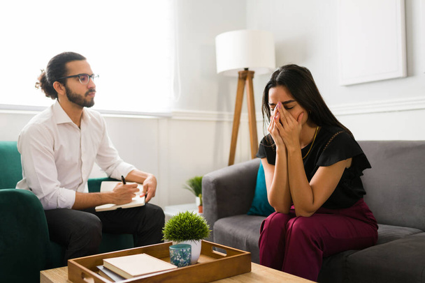 Depressed woman dealing with grief and crying with a male psychologist. Patient with depression taking therapy - Photo, Image