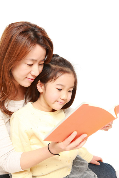 Japanese mother reading a book to her daughter - 写真・画像