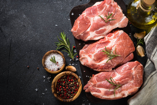 Fresh steaks with herbs and spices at black background. - Фото, изображение