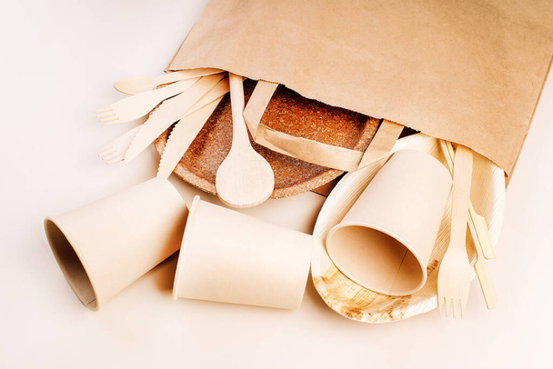 Recycling,eco-friendly concept.Disposable eco cutlery,plates,spoons,knives,forks on a light background.Craft paper bag for food delivery.Copy space.Eco craft paper tableware,cups,fast food containers. - Foto, Bild