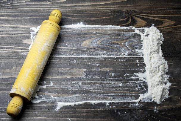 Rolling pins with flour on dark wooden table, top view, free copy space for your text, menu, recipe Rolling pin on textured bord with lights Ακατέργαστη ζύμη πεπλατυσμένη με ξύλινο πλάστη Ψήσιμο concept - Φωτογραφία, εικόνα