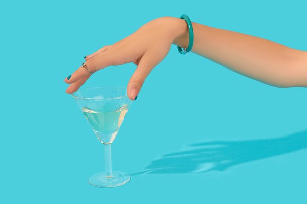 Bela mão de mulheres tratada com vidro de toque de anel na moda de coquetel no fundo azul - Foto, Imagem