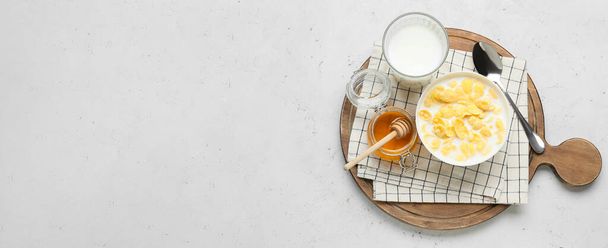 Δοχείο από τραγανές νιφάδες καλαμποκιού με γάλα και μέλι σε ελαφρύ φόντο με χώρο για κείμενο - Φωτογραφία, εικόνα