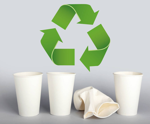 Takeaway paper cups and symbol of recycling on light background - Foto, Imagem