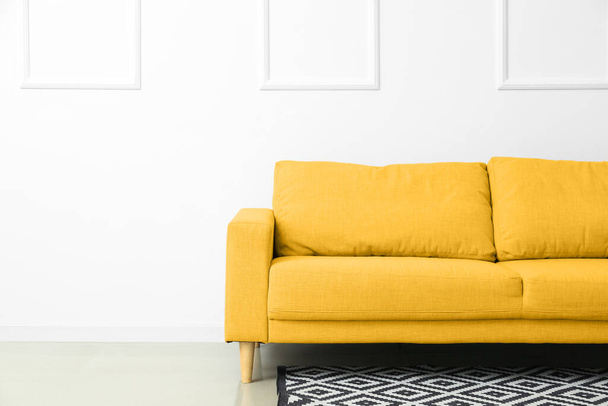 Зручний жовтий диван біля білої стіни
 - Фото, зображення